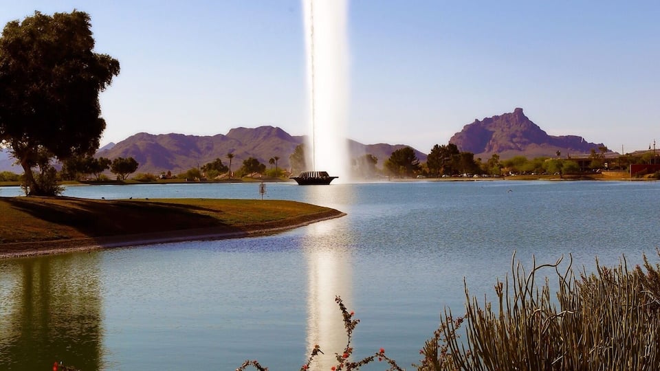 A fountain in a lake with mountains in the background.