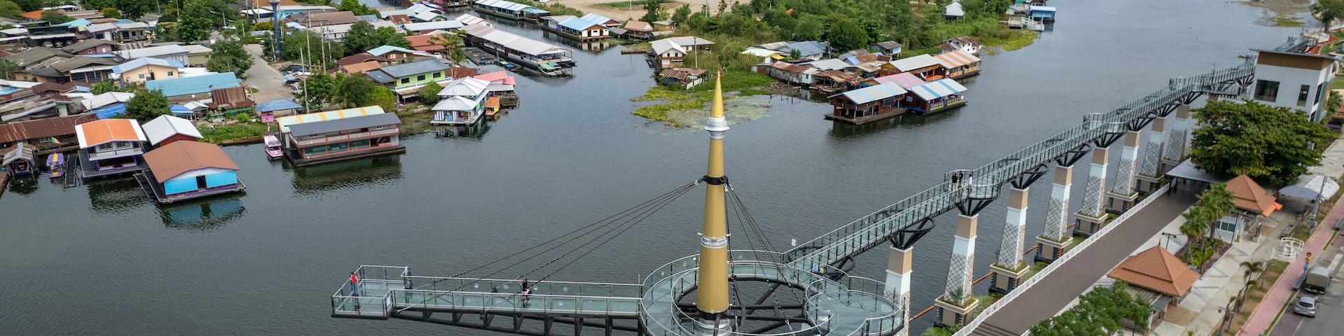 A river with floating houses, a bridge, and a monument.