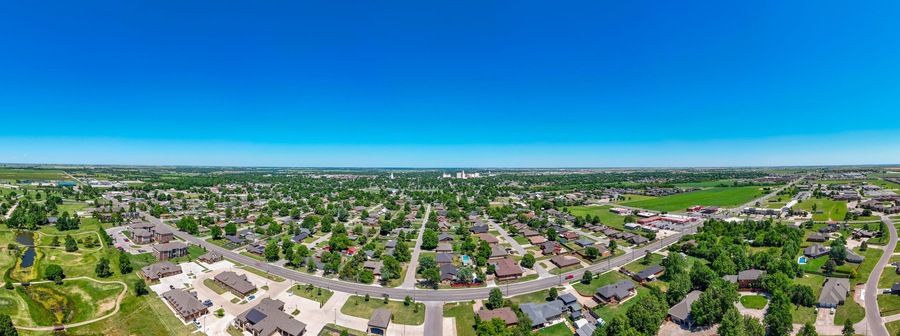 Un barrio residencial con casas, calles y un amplio campo verde.