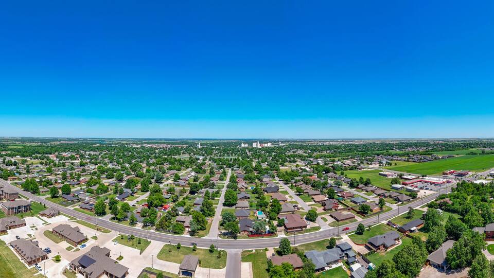 A suburban neighborhood with houses, roads, and a large green field.