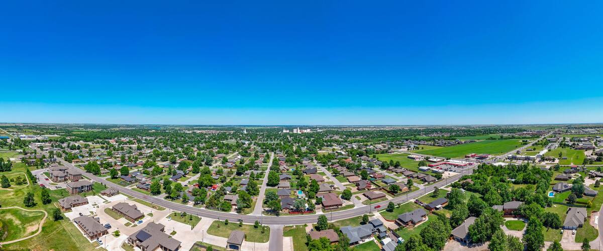 A suburban neighborhood with houses, roads, and a large green field.