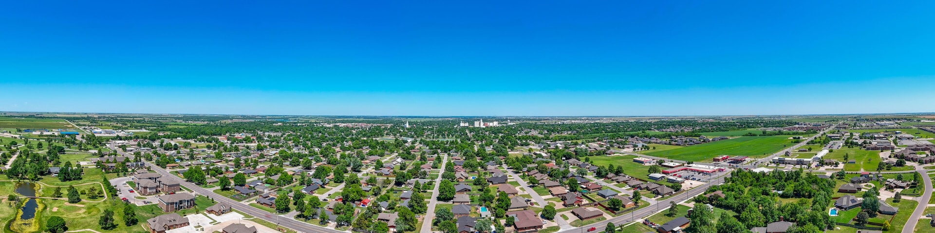 A suburban neighborhood with houses, roads, and a large green field.