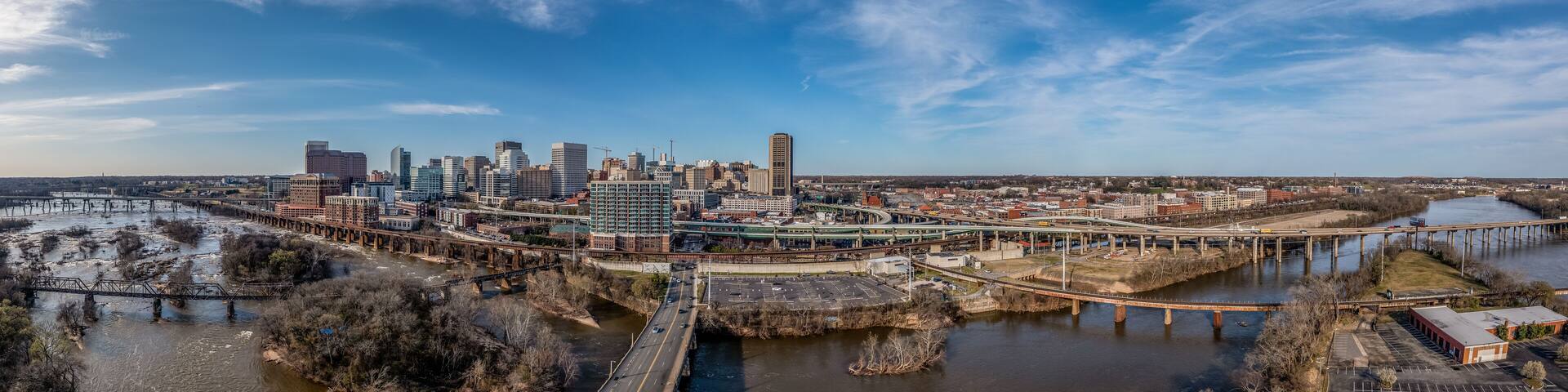 Aerial panorama of Richmond Virginia views of the Mayo and Manchester bridge over the James river, floodwall, industrial railroad tracks, downtown business district, Shockoe slip, capitol district