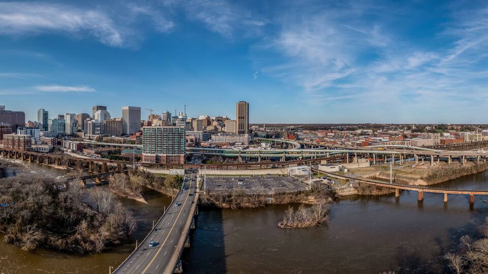 Aerial panorama of Richmond Virginia views of the Mayo and Manchester bridge over the James river, floodwall, industrial railroad tracks, downtown business district, Shockoe slip, capitol district