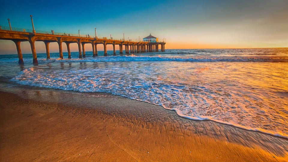 A pier extending into the ocean with waves lapping at the shore.