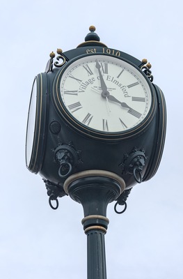 street clock detail in elmsford, new york (westchester, downtown village near tarrytown) greeburgh (ornate clock with roman numerals for hours and fancy hands) close up