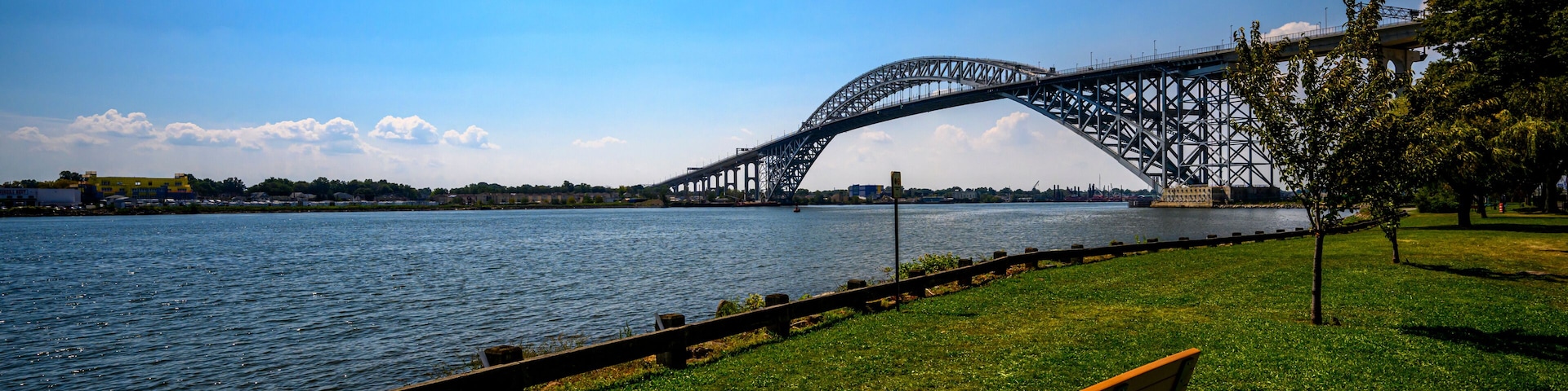 Un río con un puente, una zona verde y un banco.