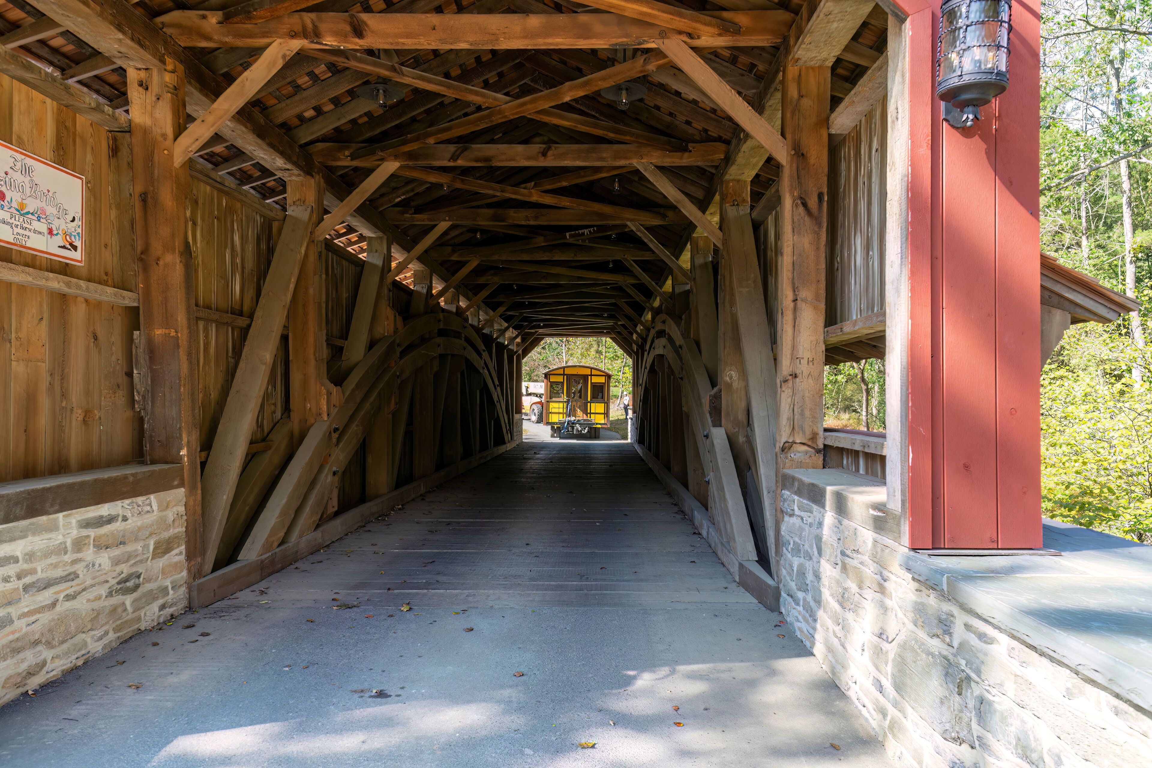 Installing a New Yellow Passenger Antique Coach Thru a Cover Bridge on to a Railroad Track