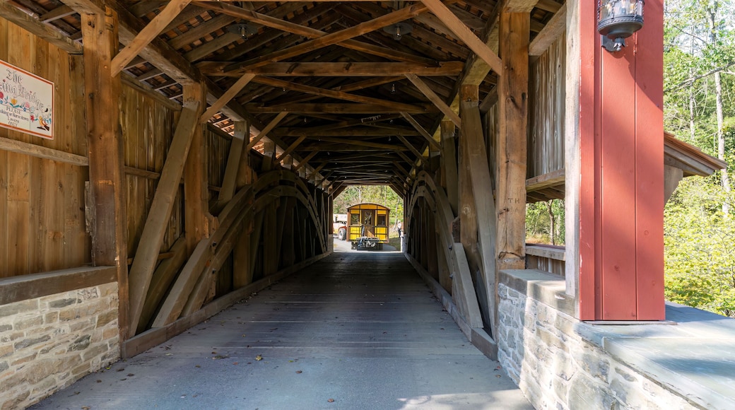 Installing a New Yellow Passenger Antique Coach Thru a Cover Bridge on to a Railroad Track