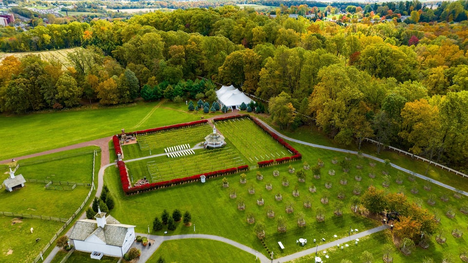 An aerial view of a park with a central lawn, a white gazebo, and surrounding trees.