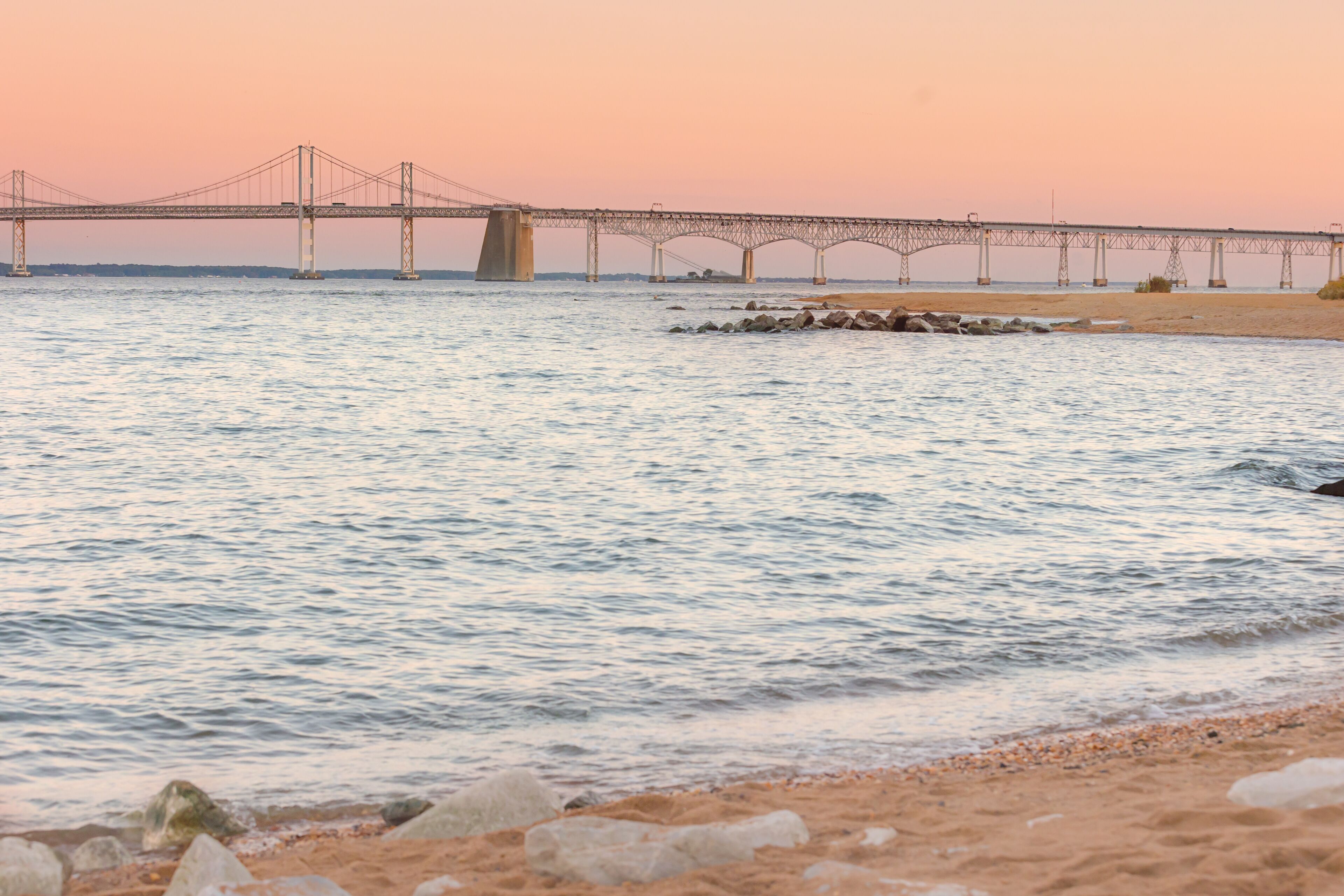 A bridge over a calm river at sunset.
