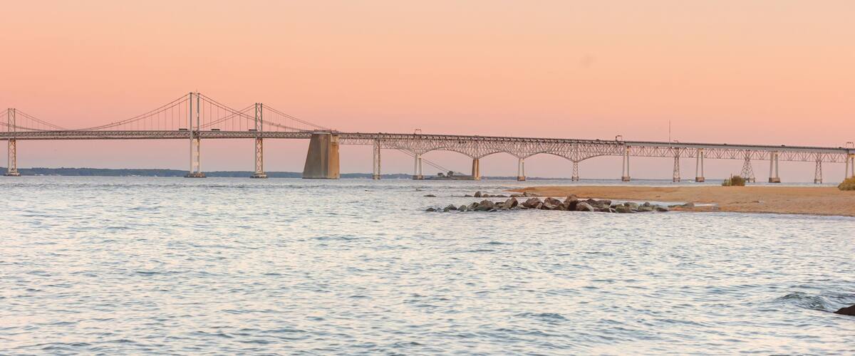 A bridge over a calm river at sunset.