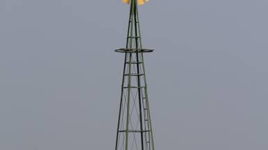 windmill in the field with green grass south of Ellsworth Kansas USA with blue sky.
