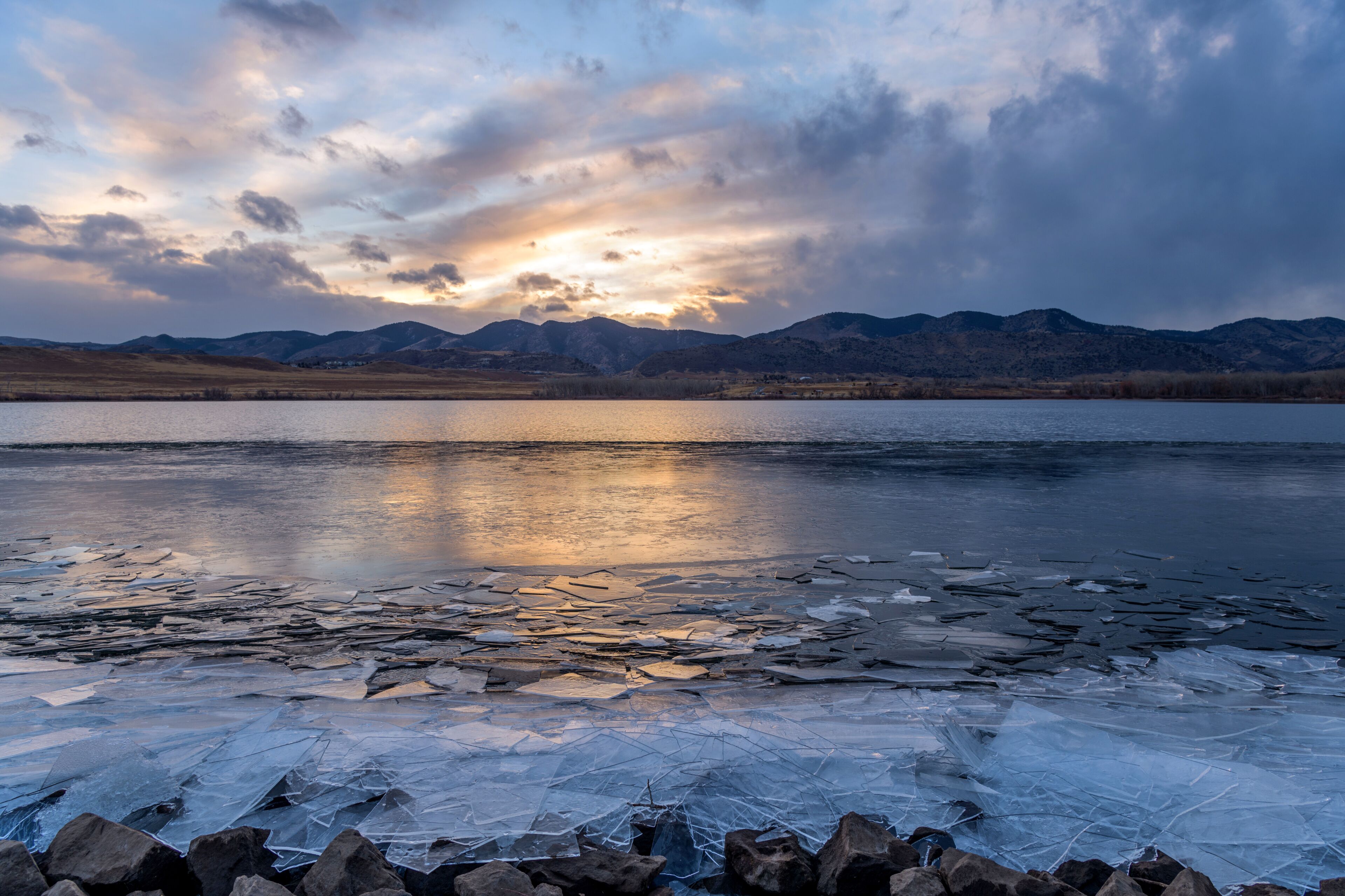 Winter Mountain Lake - A close-up view of thin broken ice pieces piling up at shore of Bear Creek Lake on a stormy December evening. Bear Creek Lake Park, Denver-Lakewood-Morrison, Colorado, USA.