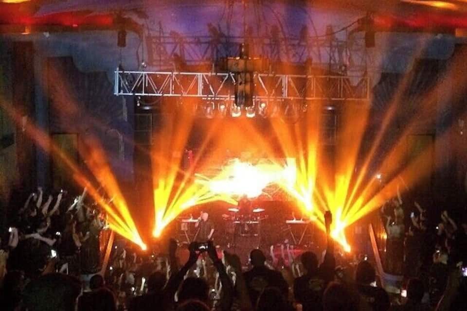 Un concierto con escenario, público e iluminación escénica.