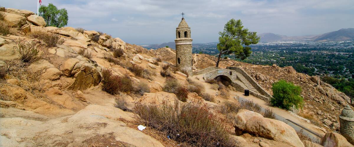 A rocky landscape with a stone tower, a flag, and a bridge.