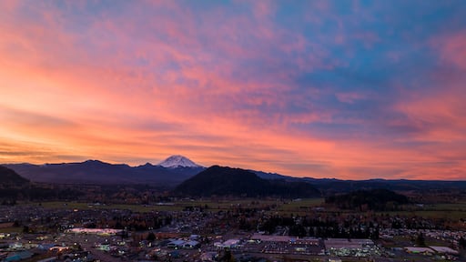 Aerial view of the town basking in the warm glow of the sunset, with Mount Rainier silhouetted against the vibrant sky, Enumclaw, Washington, United States.