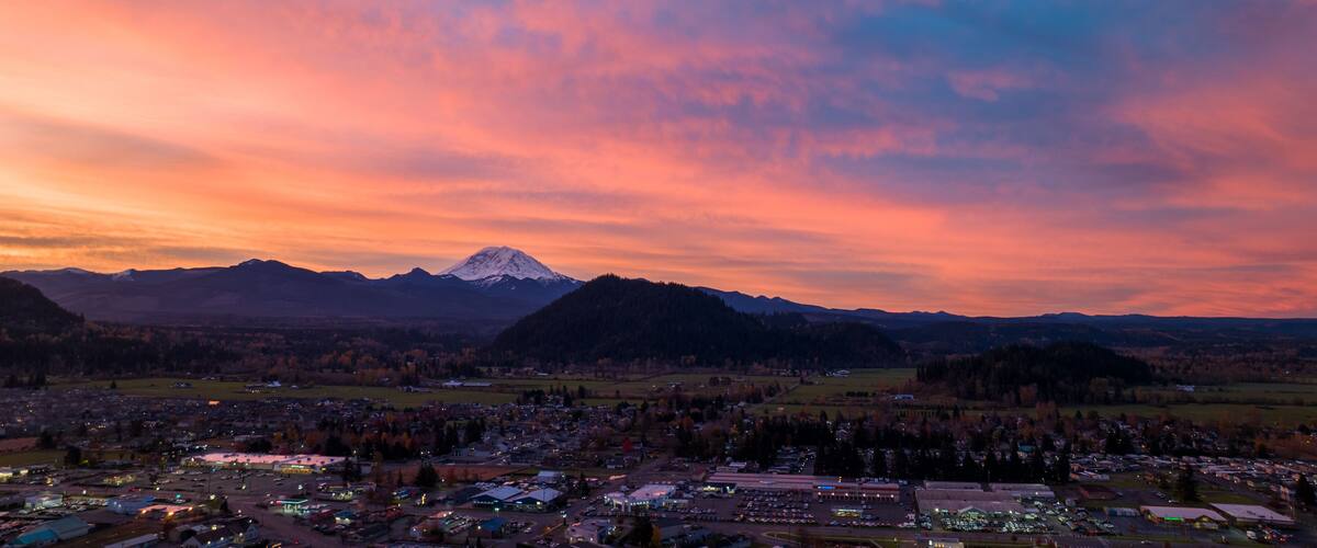 A mountain range with a snow-capped peak at sunset.