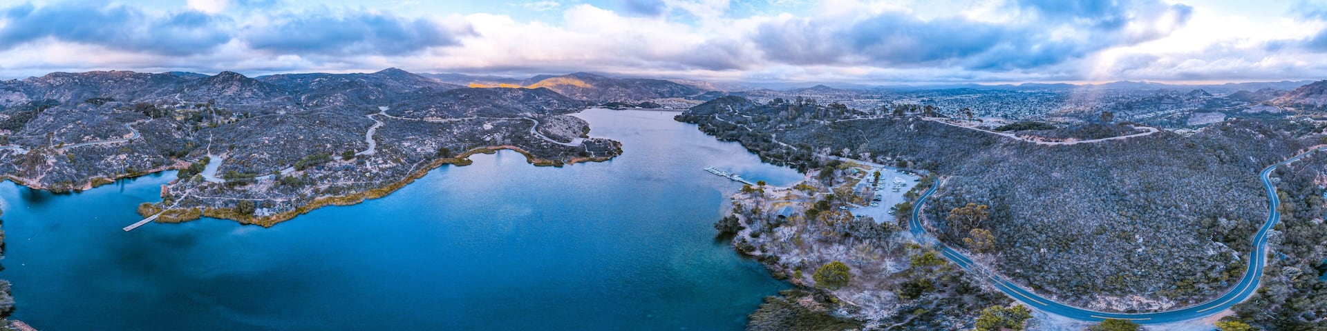 A large body of water surrounded by mountainous terrain with winding roads.