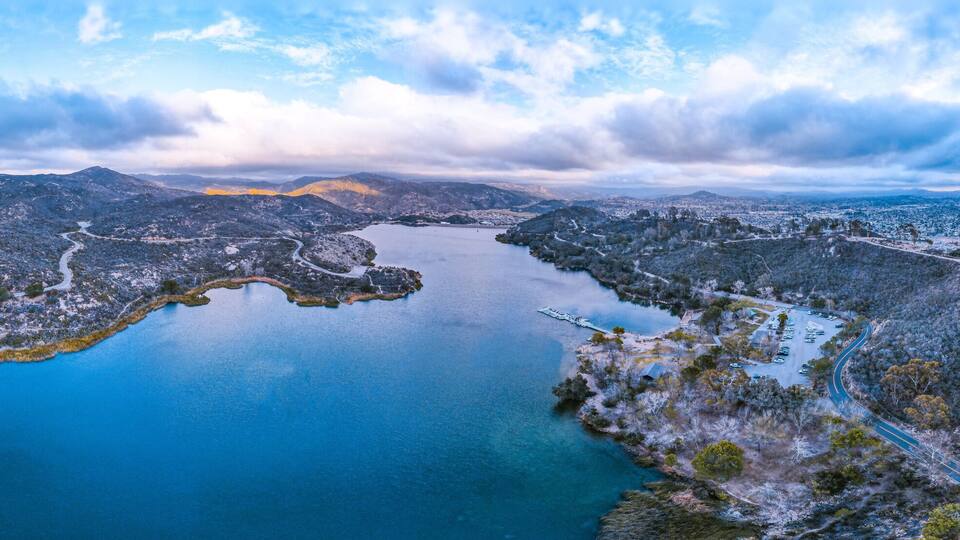A large body of water surrounded by mountainous terrain with winding roads.