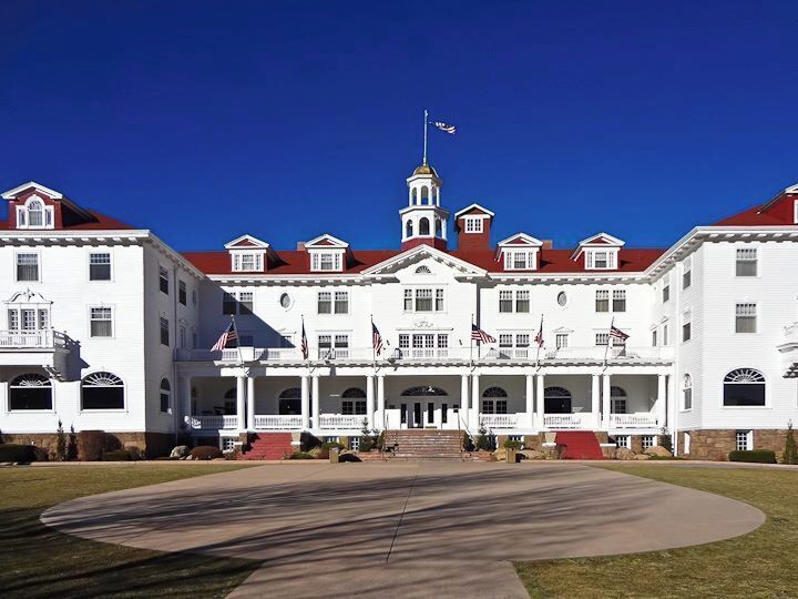A large white building with a red roof, multiple flags, and a central tower.