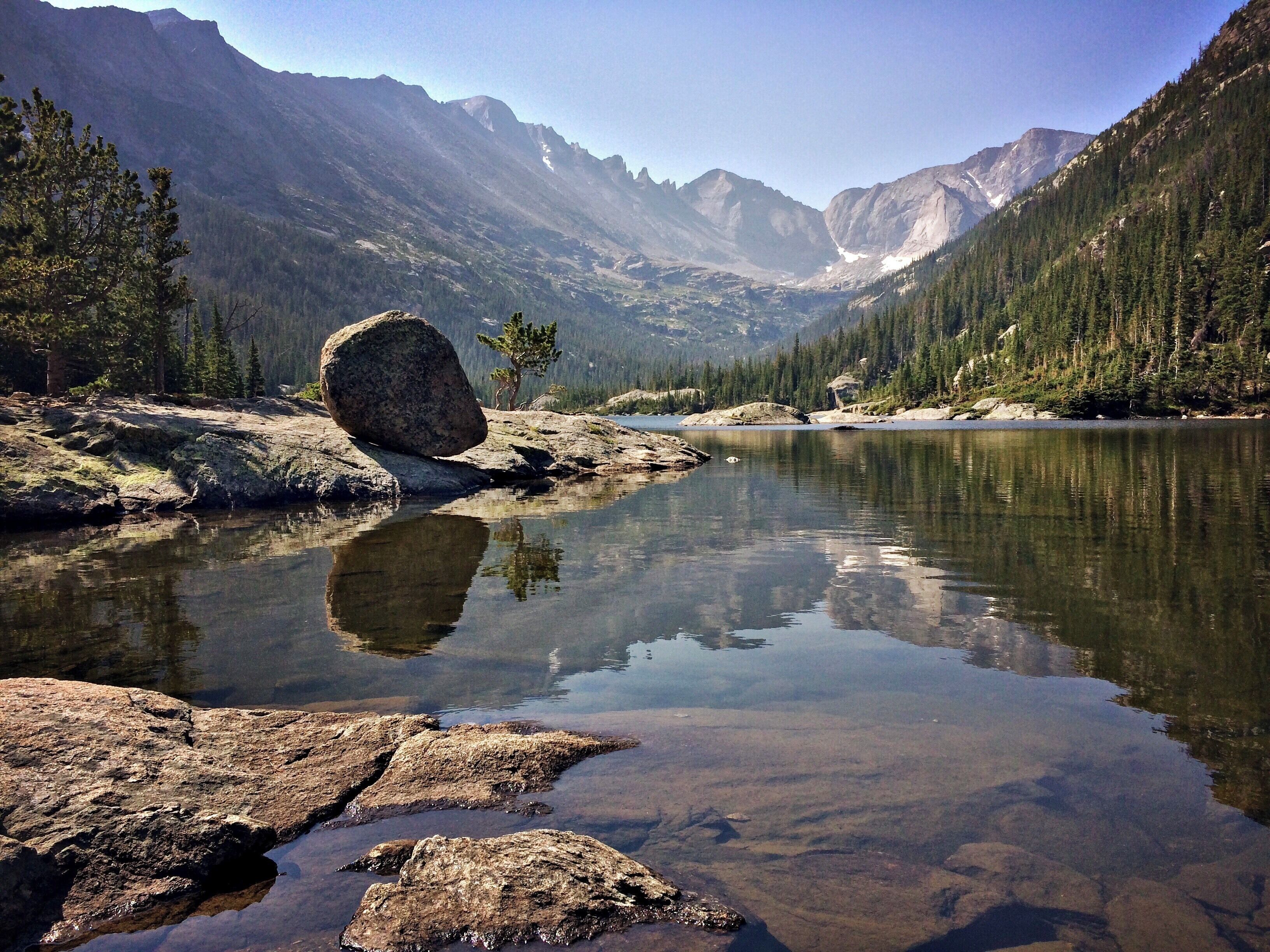 Un lago tranquilo rodeado de montañas y un bosque denso.