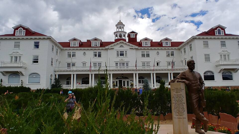 A large white building with red roofs and a statue in front.