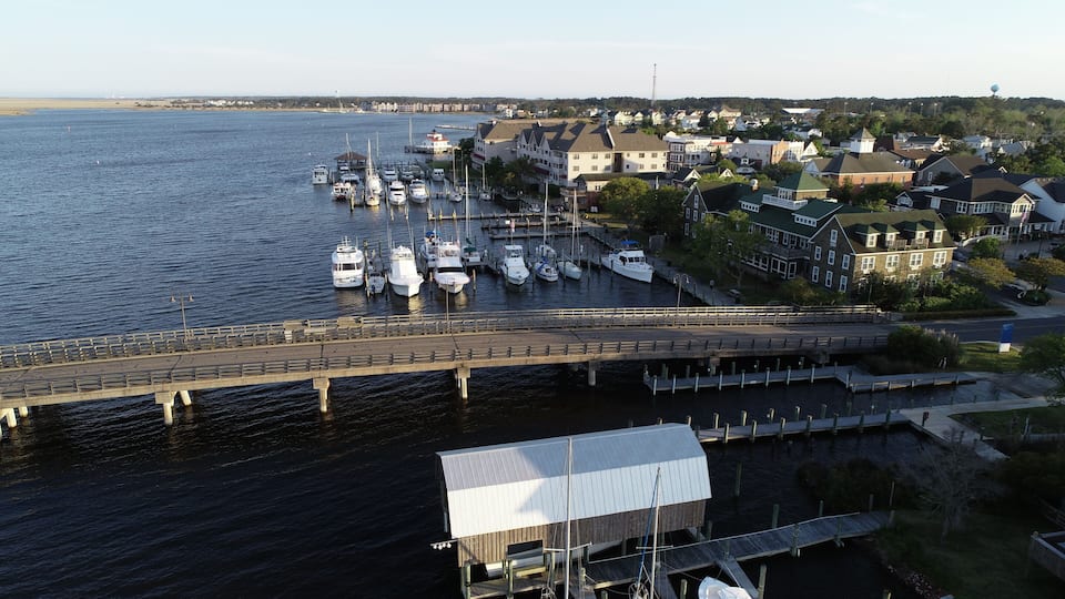 A marina with boats docked, a bridge, and residential buildings.