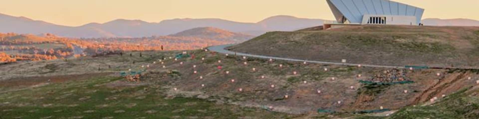 A modern building with a unique roof design on a hill overlooking a valley.