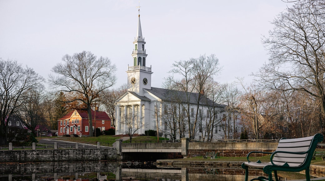 Milford Cityscape in winter over the Wepawaug River with views of the First Church of Christ in Milford built in 1824, stone bridge, and bench at the Lower Lagoon Park green in Connecticut
