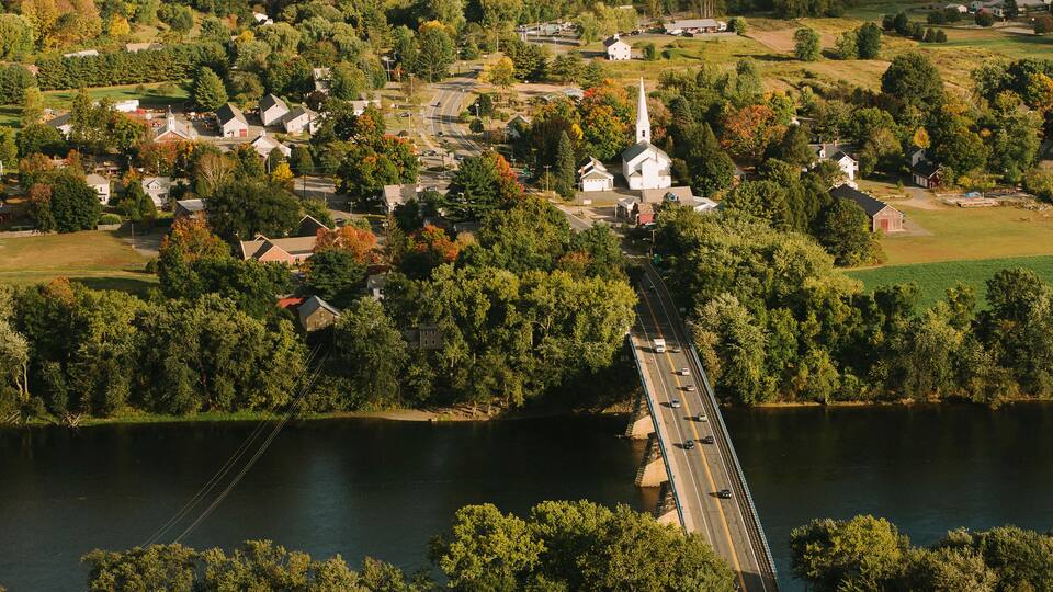 A river with a bridge, surrounded by houses and a church.