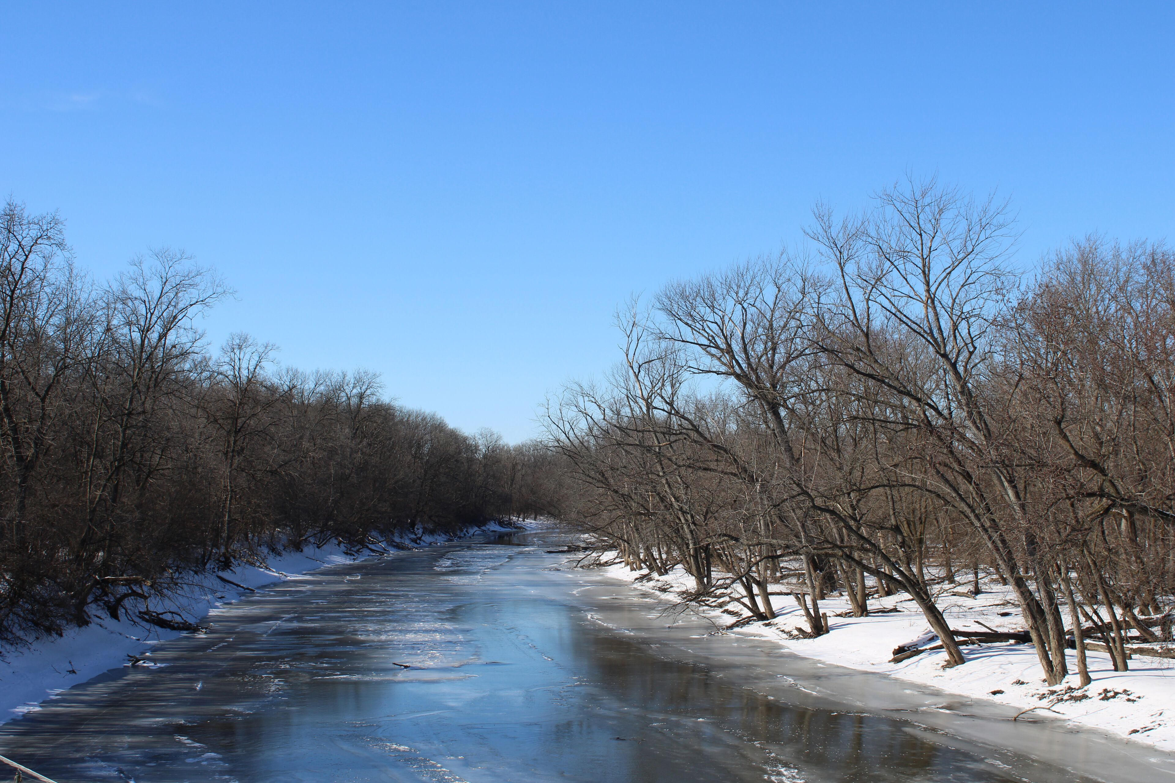 A frozen river with bare trees on both sides.