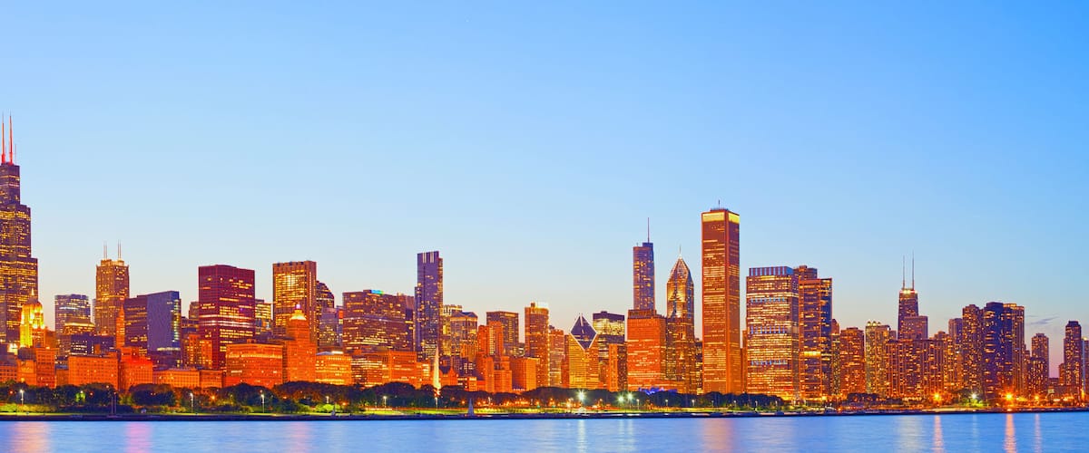 A city skyline with a prominent skyscraper and a river in the foreground.