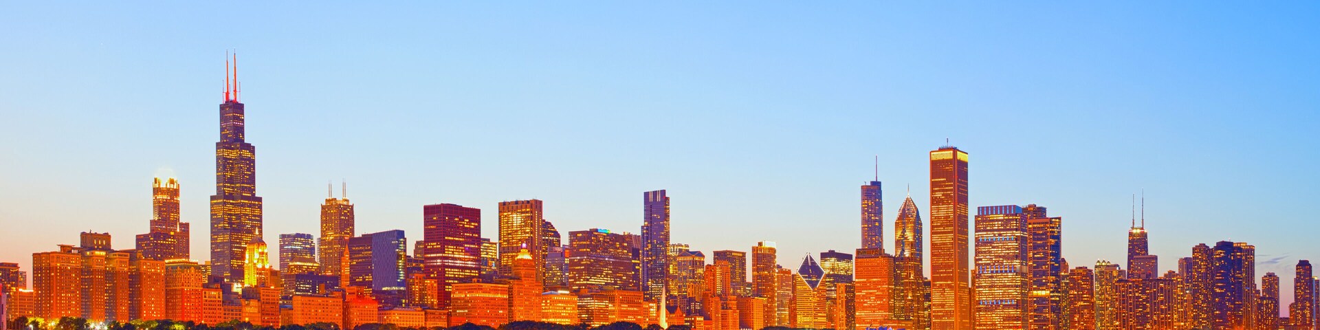 A city skyline with a prominent skyscraper and a river in the foreground.