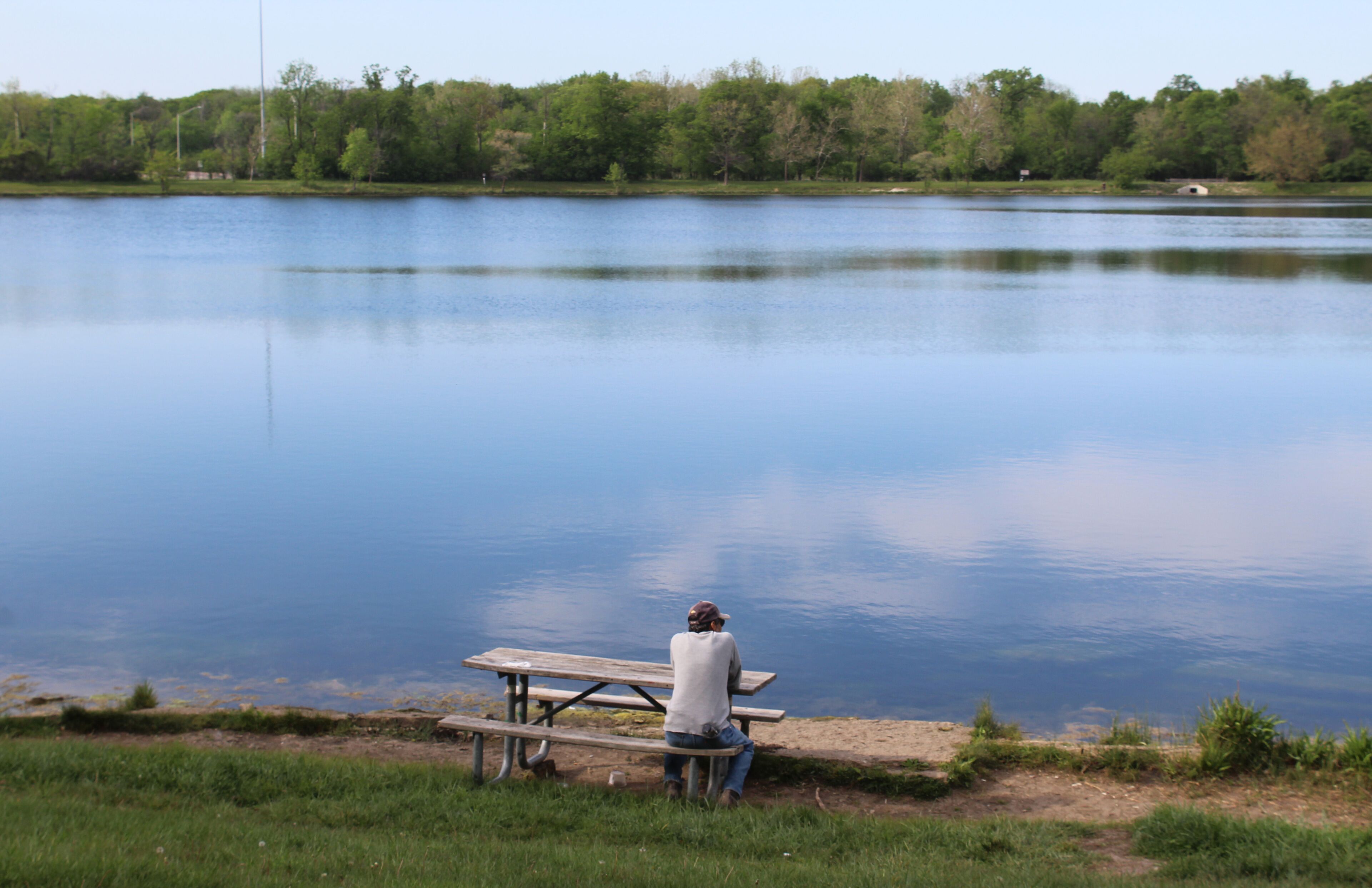Man sitting at a picnic table at Axehead Lake in Des Plaines, Illinois with a pretty reflection