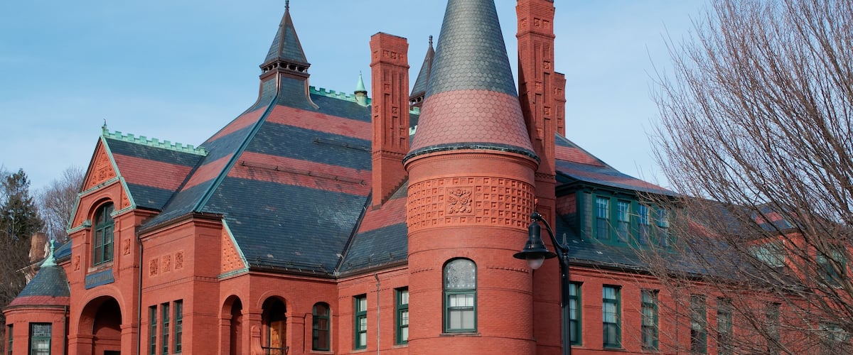 A large red brick building with a steeply pitched roof and multiple chimneys.