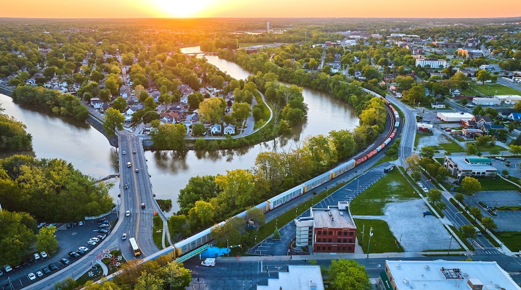 Downtown city and train with bridge over snaking riverbend to neighborhood village aerial cityscape