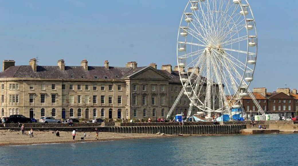Una gran noria, un paseo marítimo y edificios históricos a lo largo de la costa.