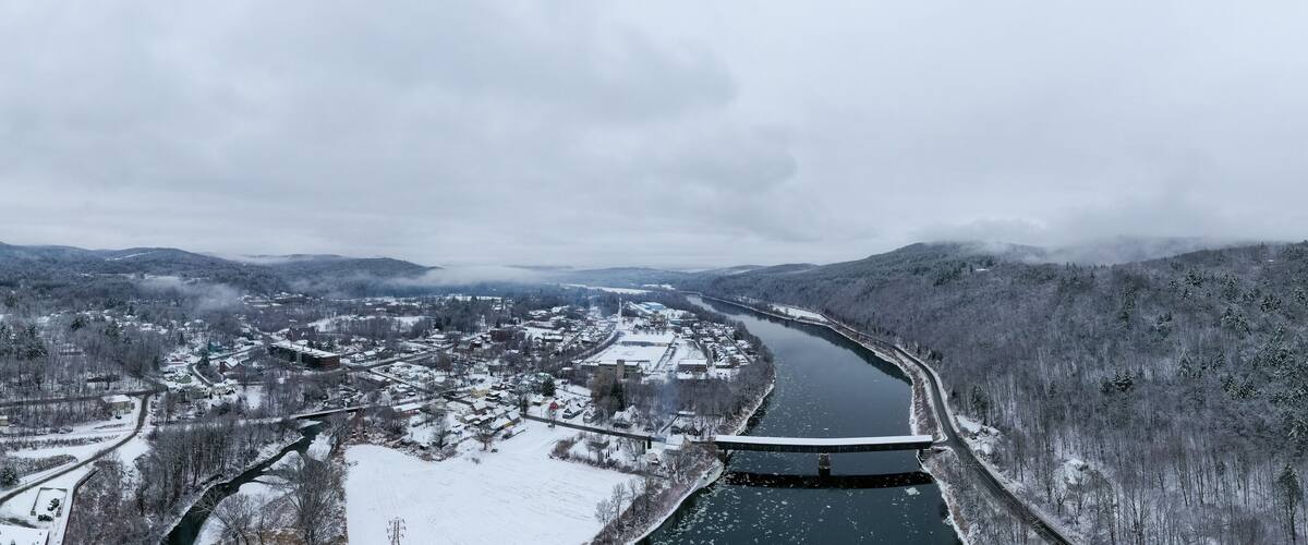 A snow-covered river valley with a bridge and a town.