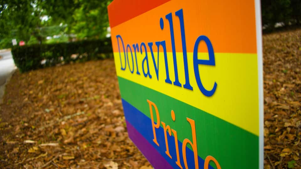 A rainbow flag sign with the word "DORAVILLE" and "Pride" written on it.
