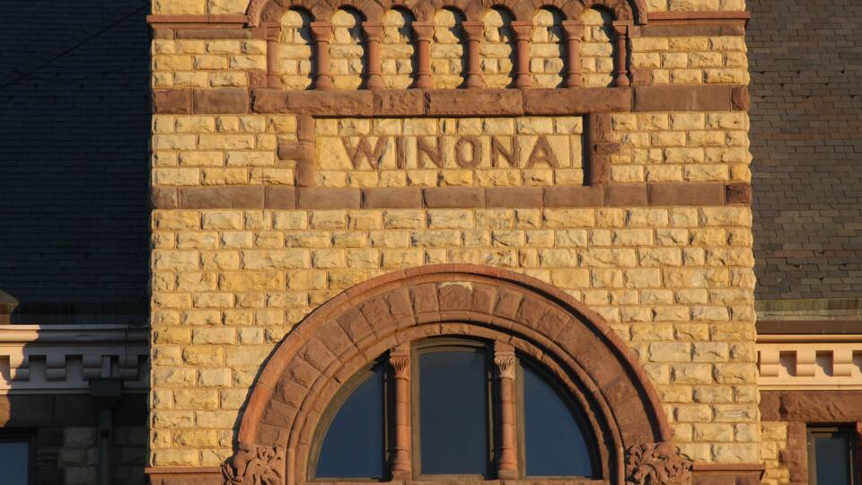 A brick building with the inscription "WINONA" and an arched window.