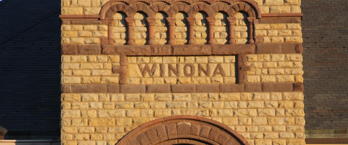 A brick building with the inscription "WINONA" and an arched window.