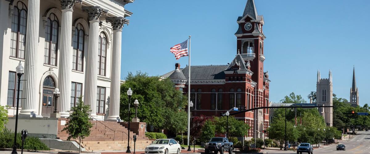 A city street with a historic building labeled 'City Hall,' a clock tower, and a church spire.