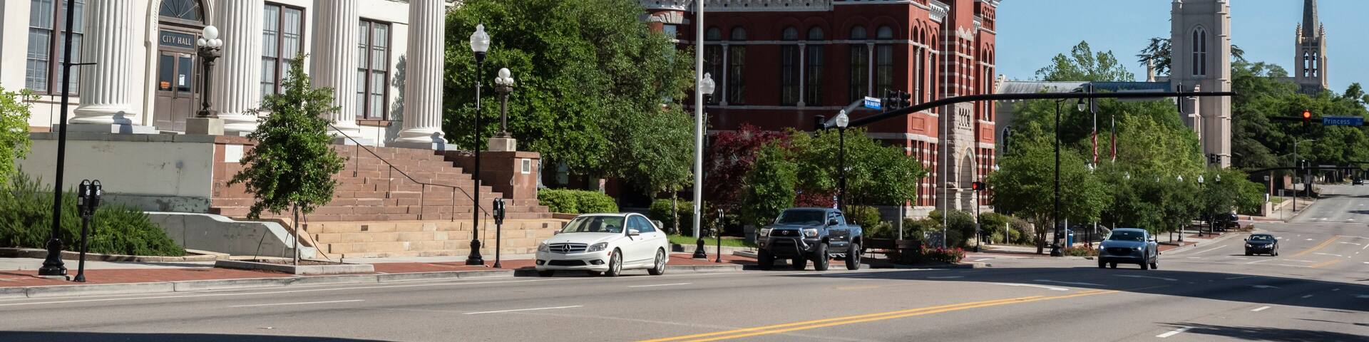 A city street with a historic building labeled 'City Hall,' a clock tower, and a church spire.