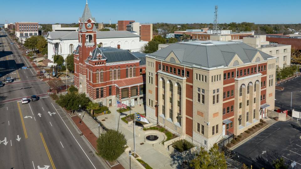 A courthouse with a clock tower, surrounded by roads and other buildings.