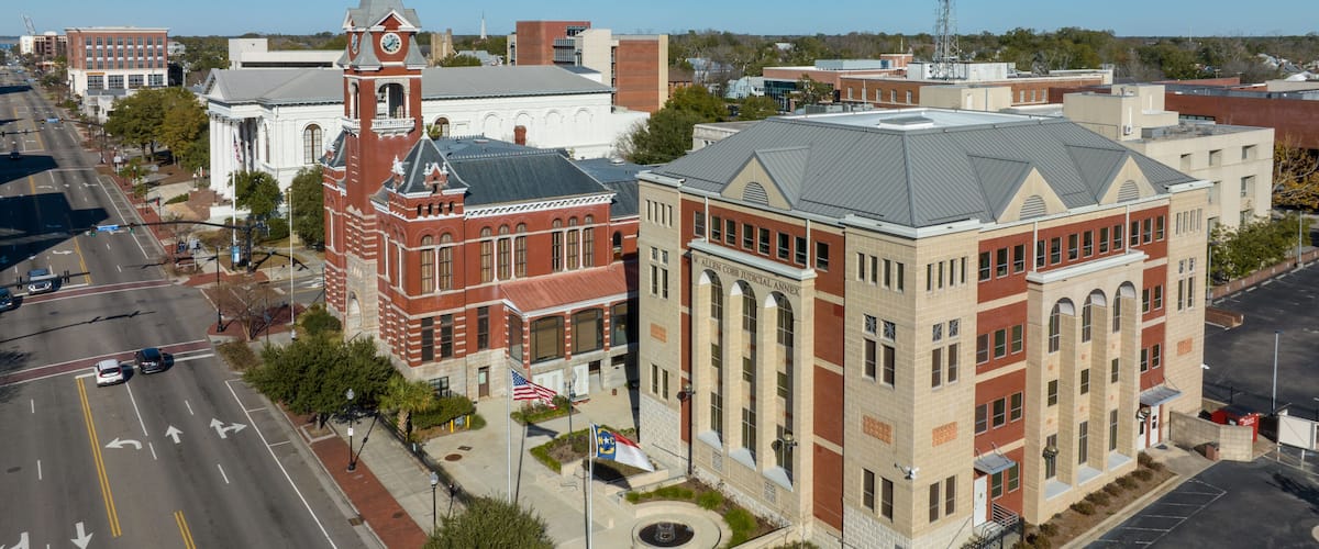 A courthouse with a clock tower, surrounded by roads and other buildings.