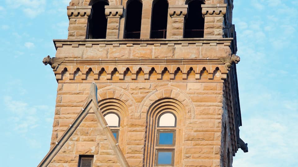 A historic stone clock tower with a pointed roof and arched windows.