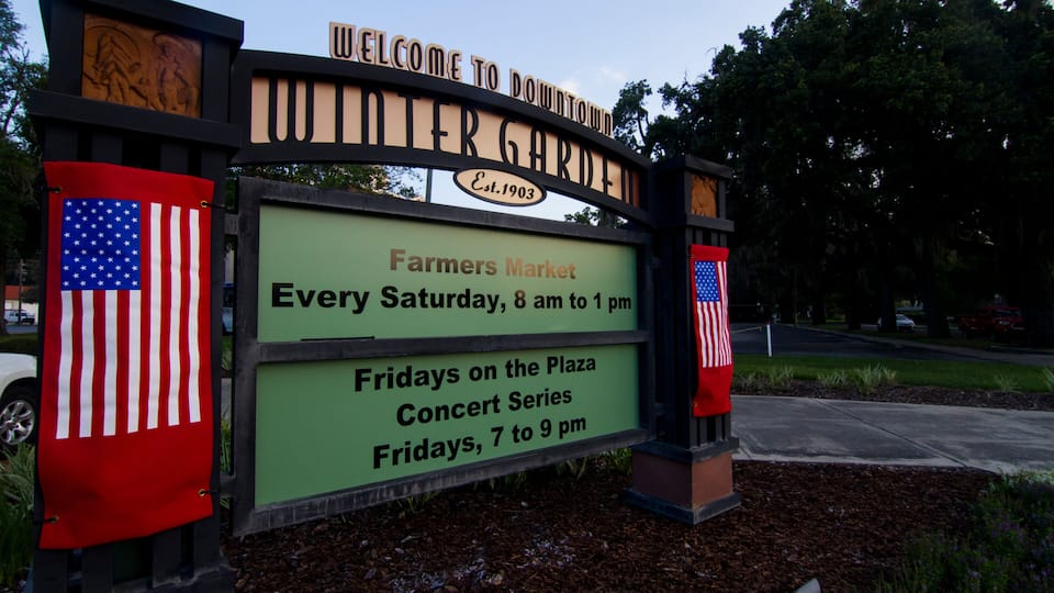 A sign for Downtown Intergarden with an American flag, Farmers Market on Saturdays, and a Concert Series on Fridays.