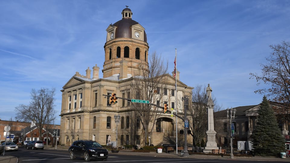A historic building with a clock tower and a statue.