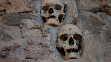 Duas caveiras humanas incrustadas numa parede rochosa.